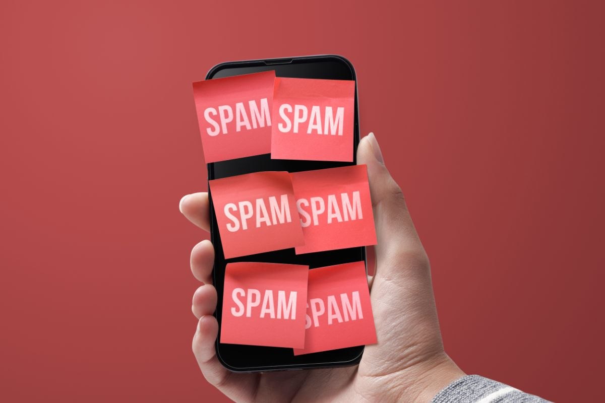 mano che mantiene smartphone con bigliettini con scritta spam