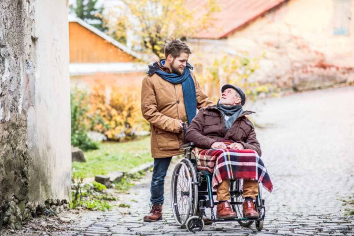 ragazzo che spinge un'anziano sulla sedia a rotelle