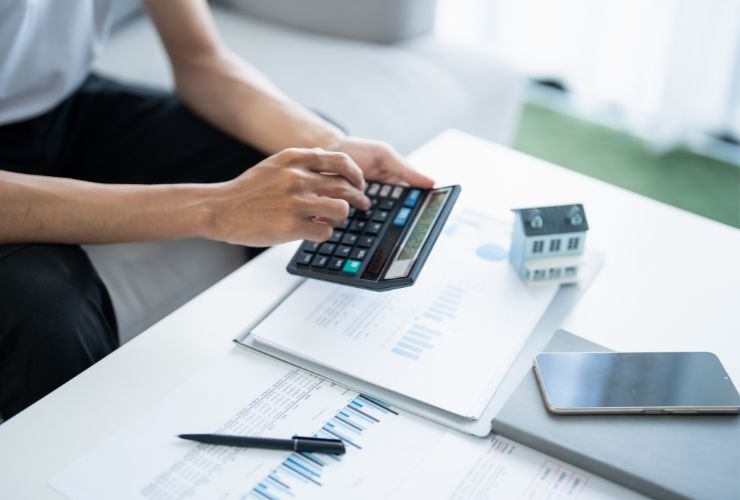 una persona che lavora con una calcolatrice vicino ad una casa piccola