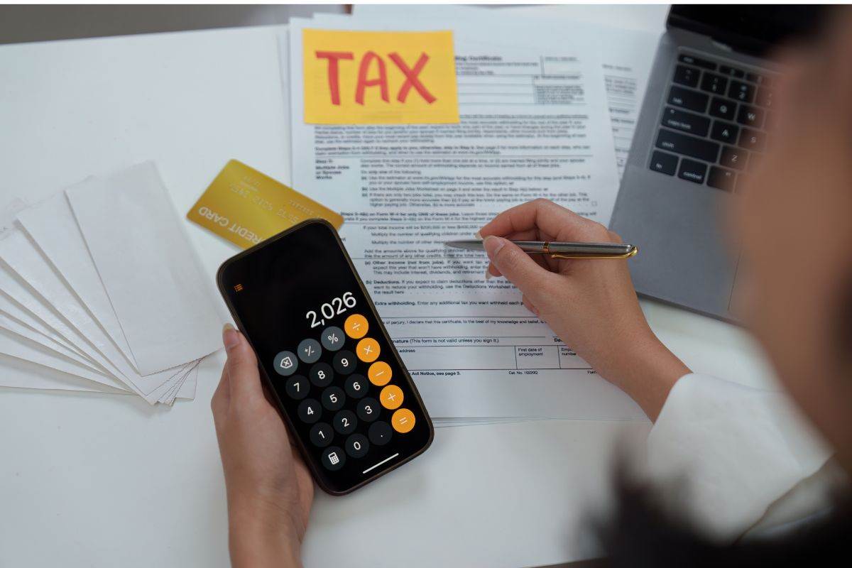la scritta tassa e una persona che lavora al computer e con una calcolatrice