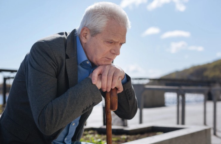 anziano triste che si appoggia ad un bastone