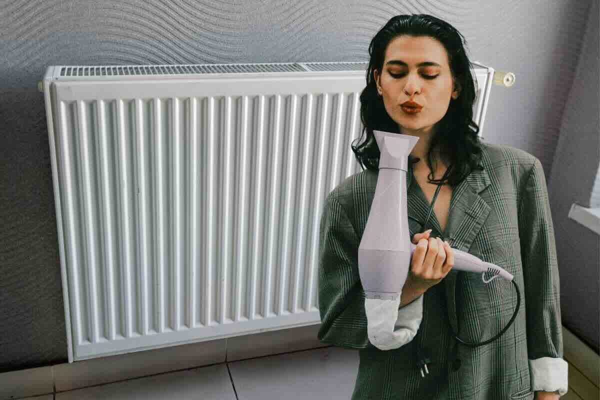 Donna con phon, dietro di lei termosifone